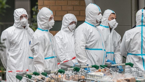 Firefighters in protective clothing prepare to distribute food to residents in Melbourne's locked-down towers.