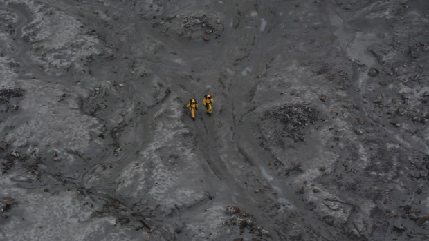 Two figures make their way towards arduous conditions to recover six bodies. The defence force team had to stop and regroup part way through the mission to asses whether they could carry on.