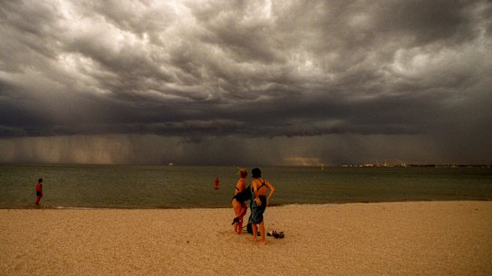 Concerned beachgoers watch on as a thunderstorm approaches on a scorching Melbourne day.