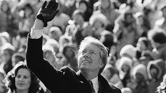 President Jimmy Carter waves to the crowd while walking with wife Rosalynn and their daughter, Amy, to the White House following his inauguration on January 20, 1977.