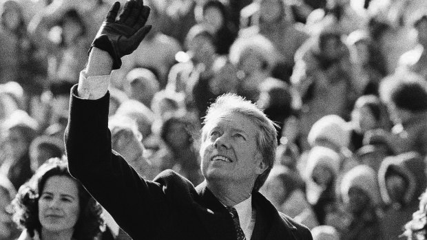 President Jimmy Carter waves to the crowd while walking with wife Rosalynn and their daughter, Amy, to the White House following his inauguration on January 20, 1977.