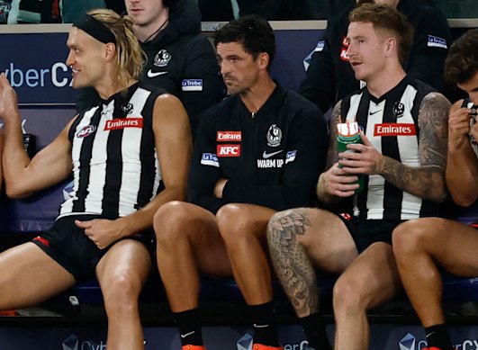 Darcy Moore (left) and Scott Pendlebury (centre) watch from the bench.