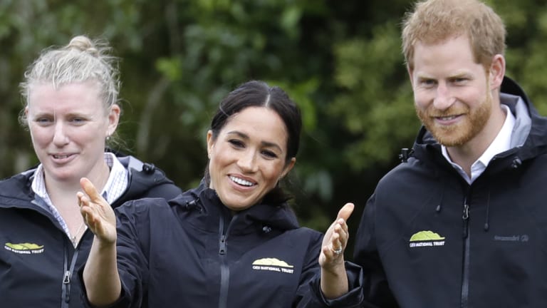Prince Harry and his wife Meghan react as they watch a 'gumboot-throwing' contest in Auckland, New Zealand.