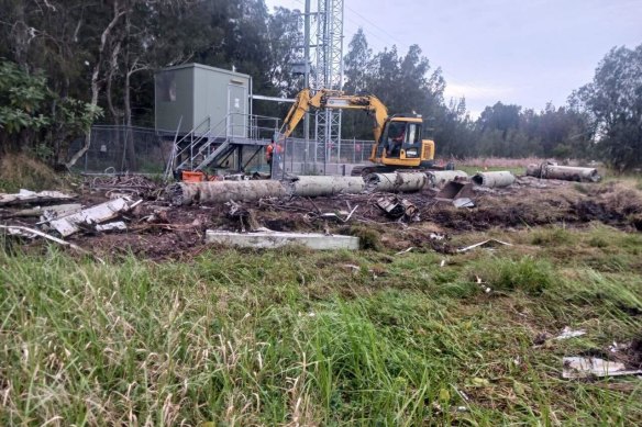 Workers clean up the damage after a vandalised mobile phone tower fell at Fullerton Cove.