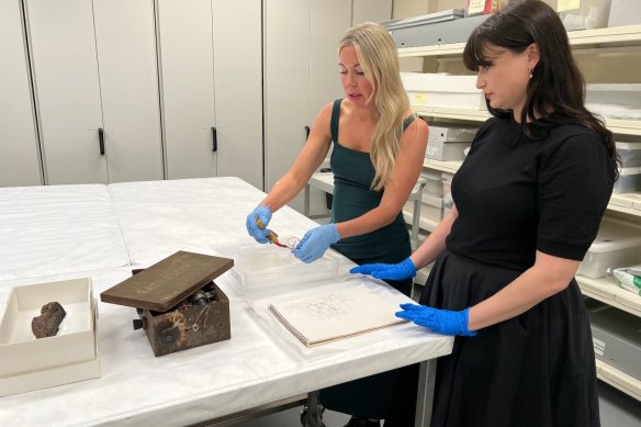 Queensland Museum senior curator Liz Bissell and assistant curator Tess Shingles examining items from the exhibition.