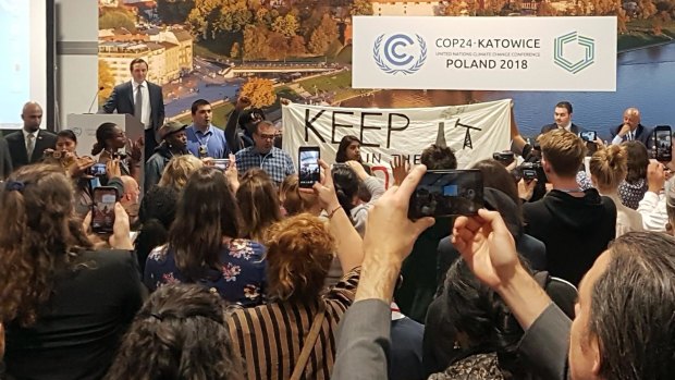 Protesters take over a stage to protest a pro-coal event at the COP24 climate talks in Katowice, Poland.