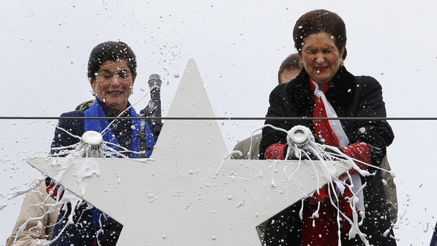 Luci Baines Johnson, left, and her sister, Lynda Johnson Robb, smash champagne bottles to christen the Lyndon B. Johnson, the third Zumwalt-class guided missile destroyer, built at Bath Iron Works.