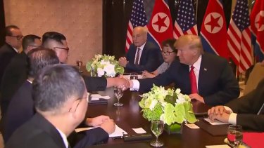 Trump and Kim shake hands with their advisers by their sides.