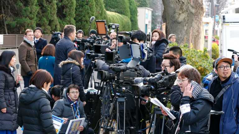 A throng of media wait outside the court room. 