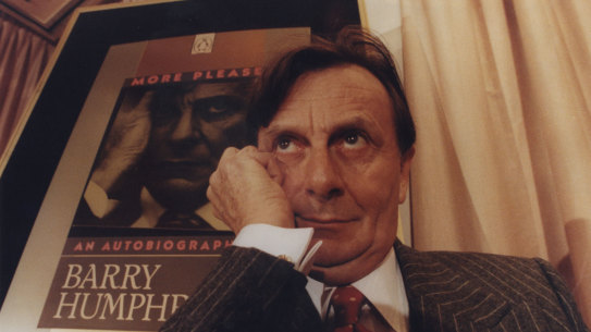 Barry Humphries with the cover of his autobiography behind him.