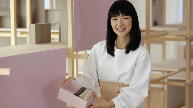 Marie Kondo pretending to be happy while putting some boxes away.