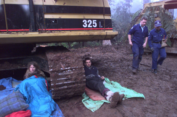 Demonstrators lay under a log grabber.