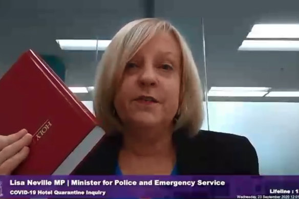 Lisa Neville taking an oath on the Bible before giving evidence at the hotel quarantine inquiry.