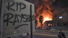 A Wendy's restaurant, background, burns Saturday in Atlanta after demonstrators allegedly set it on fire. 