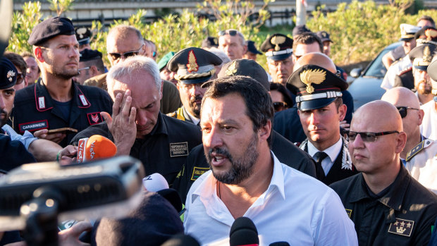 Matteo Salvini, Italy's deputy prime minister, centre, speaks to the media as he visits the Morandi motorway bridge after it partially collapsed in Genoa, Italy. 