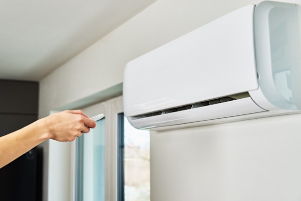 Hand adjusting temperature on air conditioner with remote control