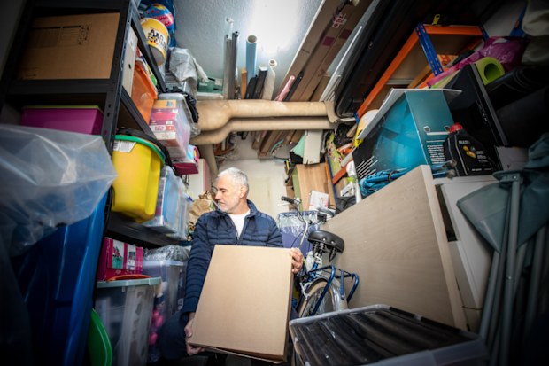 Man trying to organise a fully packed garage shelves