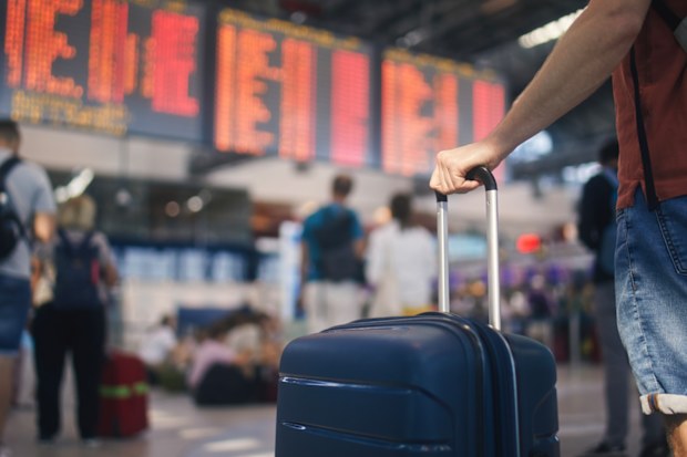 Man looking at board of cancelled flight information in airport terminal