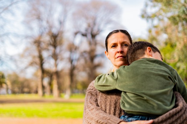 Mid adult woman holding her son on lap at public park
