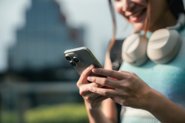Gen Z woman scrolls on her smartphone, eyes locked on a viral video trending on her for you page, fully immersed in pop culture, internet humor, and the fast-paced world of short-form content