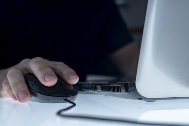 CLOSE UP OF A MALE HAND ON THE MOUSE USING LAPTOP ONLINE. TELECOMMUTING CONCEPT.
