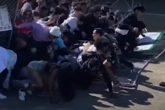 A still from US television shows the crowd rushing through the gates towards the stage. 