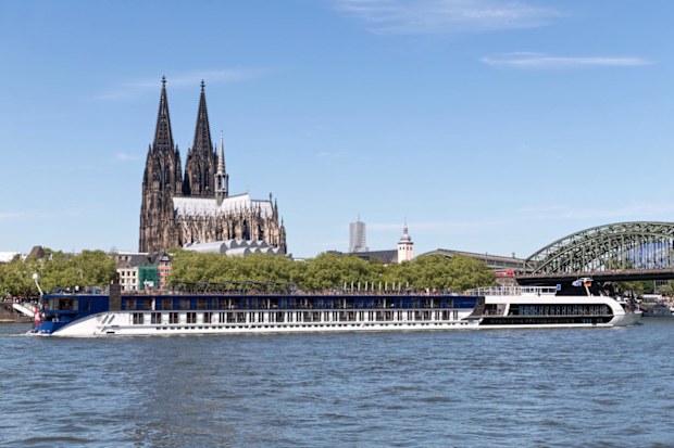 A river cruise ship passing Cologne Cathedral in Germany.