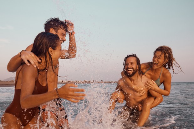 Carefree friends having fun while playing during summer day in sea