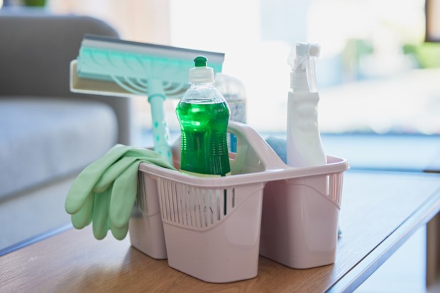 Cleaning caddy with sprays, cloths and squeegee on coffee table ready to start cleaning