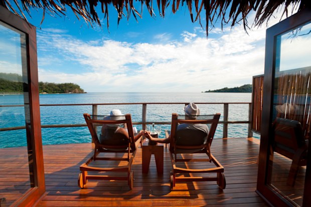 Couple relaxing on sun lounges in an over water bungalow
