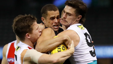 Carlton's Ed Curnow is wrapped up by Jack Billings and Jack Steele.