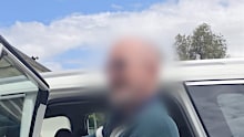 In a supplied image obtained on Wednesday, March 25th, 2026, 76-year-old bank robber and murderer Alexander Robert MacDonald is escorted by detectives to Tweed Heads Police Station.