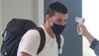 Carlton's Matthew Kreuzer - with his family - undergoes a temperature check at Melbourne Airport before leaving for the AFL's transition hub on Thursday. 