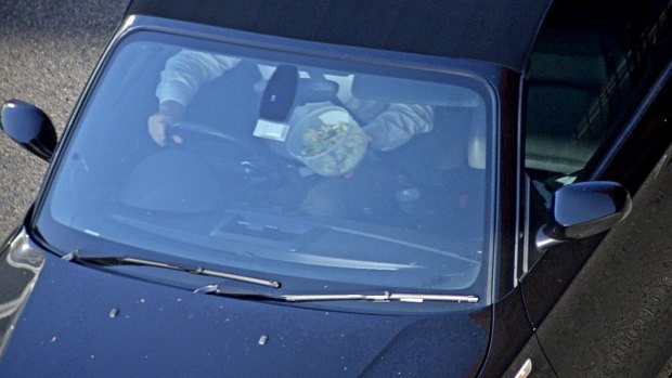 A man enjoys a meal while driving at high speed.