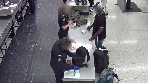 ABF officials search the man at Perth International Airport. 