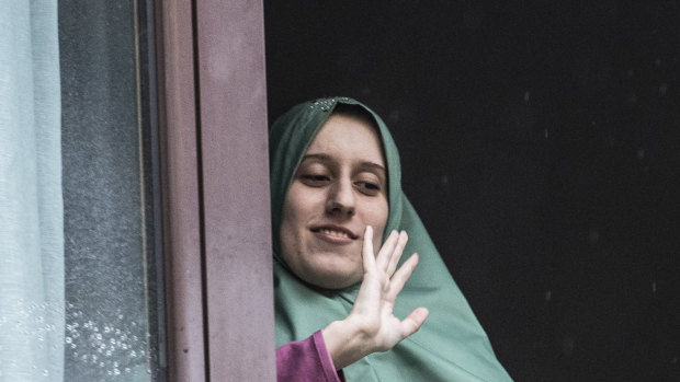 Silvia Romano gestures from a window after she arrived at her home, in Milan.