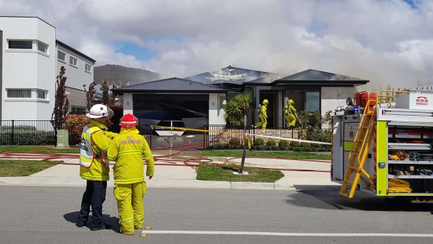 Firefighters at the scene of a blaze that significantly damaged a display home in Kondelea Way, in Denman Prospect.