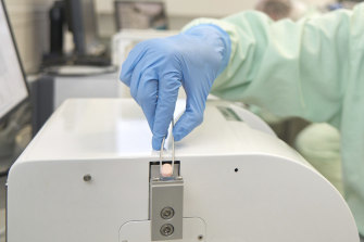 A lab technician with a Paxlovid tablet.