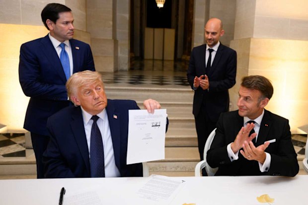 Donald Trump holds up the Iran deal paperwork he just signed at Versailles.