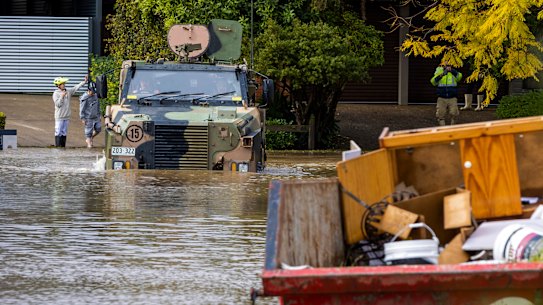 An Australian Army Bushmaster Protected Mobility Vehicle drives through a flooded street in McGrath Hills near Windsor.