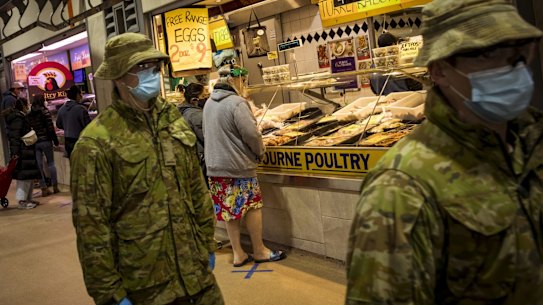 Members of Victoria Police aided by ADF soldiers patrol the Queen Victoria Market.