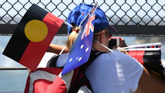 Free flags were used as fans and shade as thousands walked around Circular Quay to partake in Australia Day events.