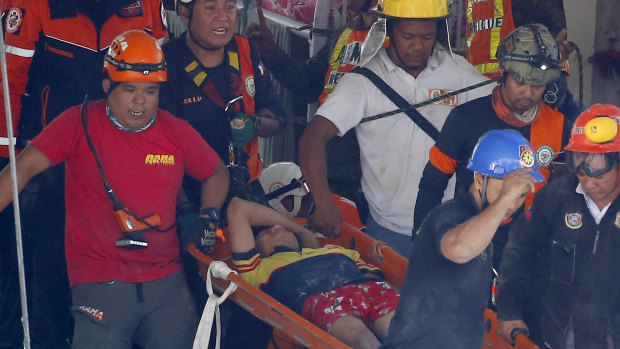Rescuers carry an earthquake survivor after being pulled out from the rubble of a supermarket following a 6.1 magnitude earthquake in Porac township, Pampanga, north of Manila.