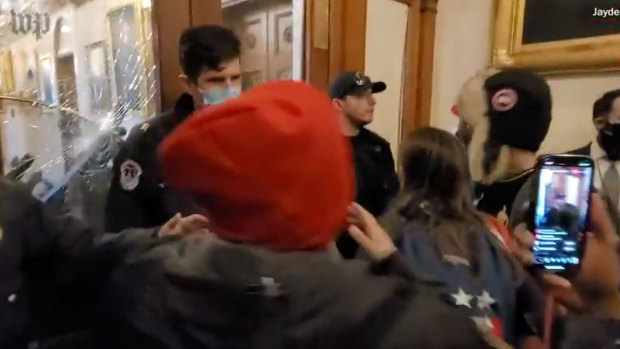 Ashli Babbitt, centre right, with the star backpack, appears in a video obtained by the Washington Post showing the mob at the doors of the Speaker's Lobby.