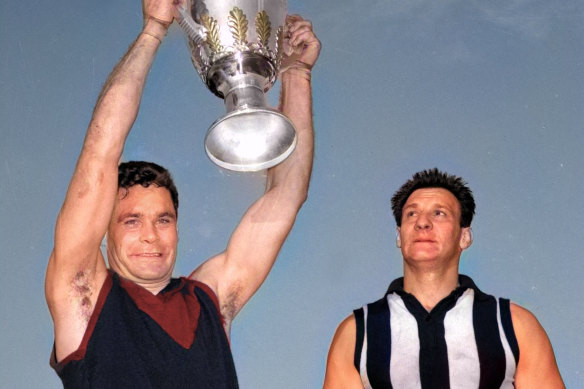 Melbourne captain Ron Barassi holds up the 1964 VFL premiership cup as Collingwood captain Ray Gabelich looks on.