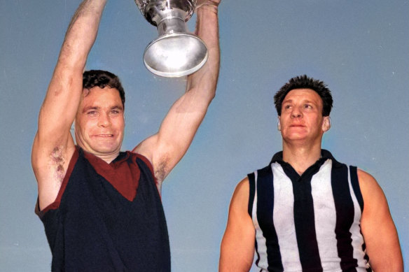 Melbourne captain Ron Barassi holds up the 1964 VFL premiership cup as Collingwood captain Ray Gabelich looks on.