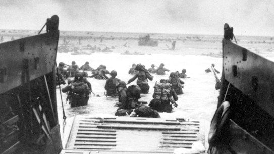 American infantrymen wade ashore off the ramp of a Coast Guard landing craft during the invasion of the French coast of Normandy in World War II. 