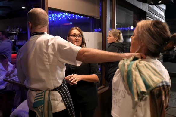 John Mountain tries to push protesters out the door of his restaurant.