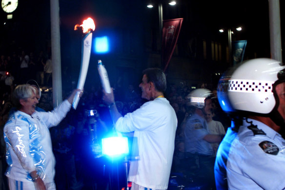 Dawn Fraser and Murray Rose exchange the Olympic flame in George Street, Sydney in 2000.
