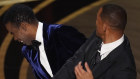 Chris Rock, left, reacts after being hit on stage by Will Smith while presenting an award at the Oscars.